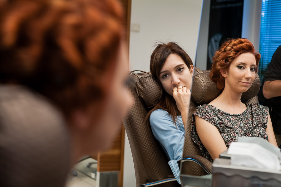 friend watches bride as she is looking at herself at the mirror