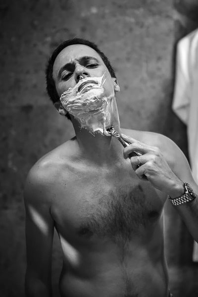 Groom shaving in bathroom mirror