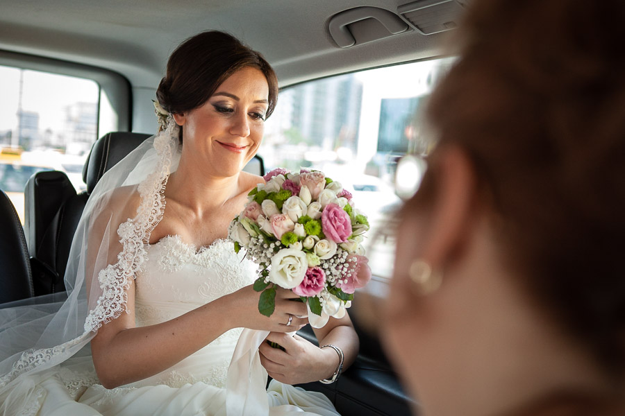 bride cgeking her bouquet in the car