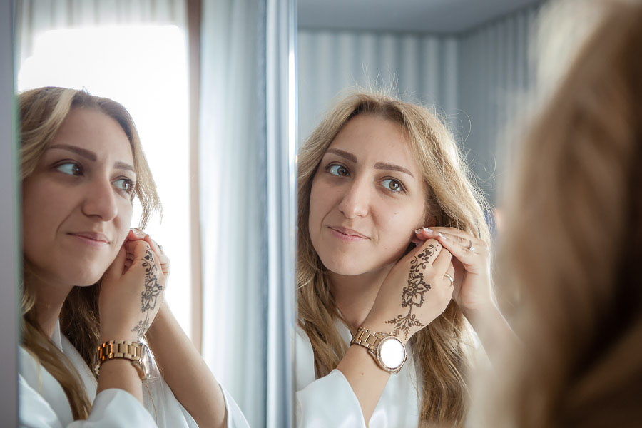 Bride putting on earing on mirror