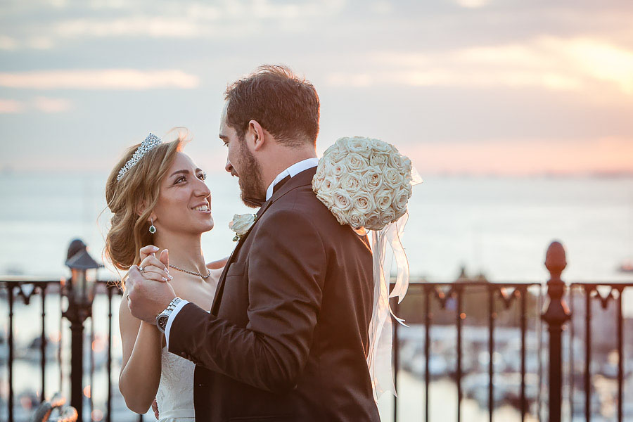 Bride and groom dance on rooftop against sea view