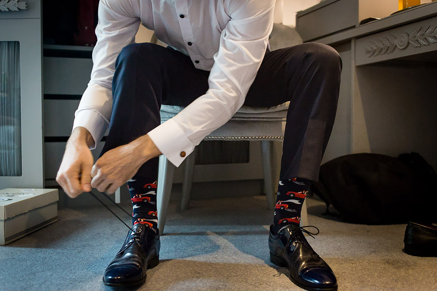 groom wearing colourful socks tying his shoes
