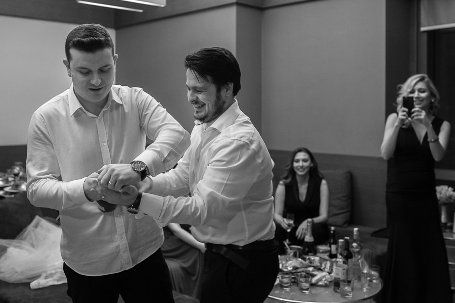 groom and friend opening a bottle of champagne